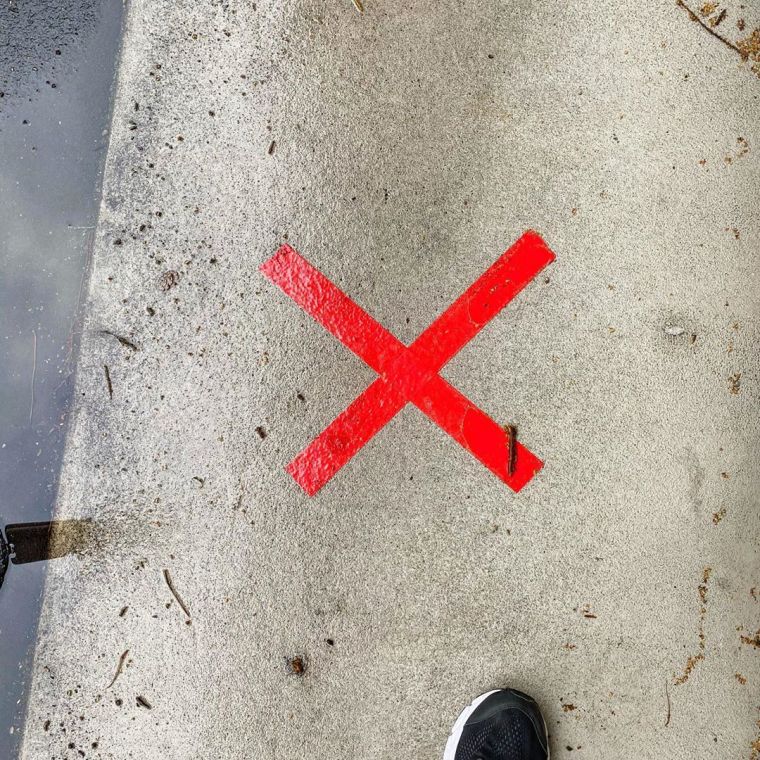 Red cross on the pavement to indicate social distancing space at the doctor's office while waiting for the influenza immunization in 2020