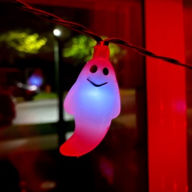Ghost light on a string of Halloween lights hanging in the front window of the house